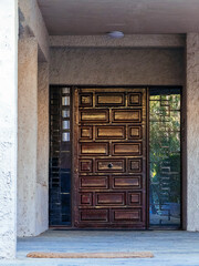 A contemporary design house entrance with a wooden door between glass openings. Travel to Athens, Greece.