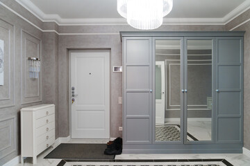 Spacious hallway in the apartment with gray walls, shoe rack and large mirrors
