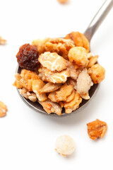 Muesli oat cereals with raisins, dried fruits and sunflower seeds in iron spoon on white background. Close-up