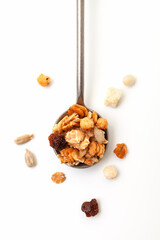 Muesli oat cereals with raisins, dried fruits and sunflower seeds in iron spoon on white background