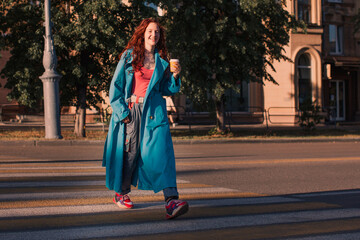 Fototapeta na wymiar Stylish happy young woman with up of coffee walking in city
