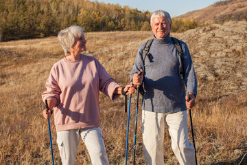 Happy middle age woman and man walking with Scandinavian sticks in autumn forest - 781102956