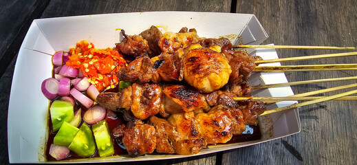 Lamb grilled satay served with barbecue savory sauce and pickled onion, chili and cucumber,...
