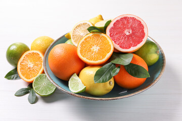 Different cut and whole citrus fruits on white wooden table