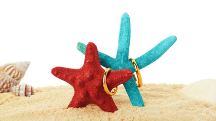 Honeymoon concept. Two golden rings, sea stars, seashells and sand isolated on white
