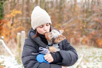 Young woman with yorkshire terrier dog in the park in winter