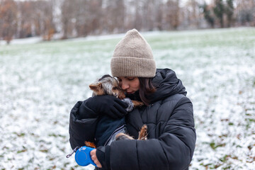 Young woman with her little dog in the park in winter time.