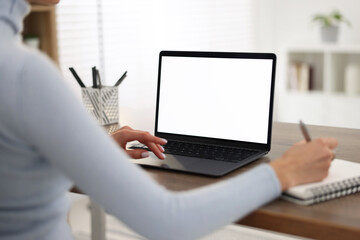 Young woman writing down notes during webinar at table indoors, closeup