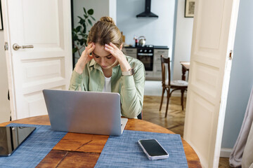 A woman is consumed with stress as she confronts a complex problem on her laptop, a moment of...