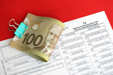 Canadian T4 tax form Statement of remuneration paid lies on table with canadian money bills close up. Taxation and annual accountant paperwork in Canada