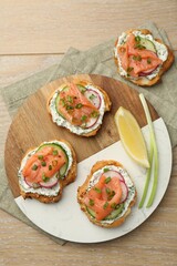 Tasty canapes with salmon served on wooden table, top view