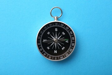 One compass on light blue background, top view. Tourist equipment