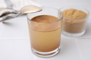 Soluble fiber with water in glass and powder on white tiled table, closeup