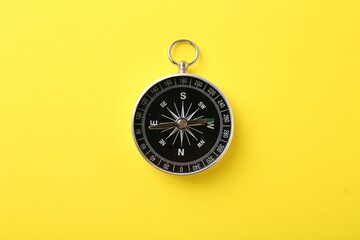 One compass on yellow background, top view. Tourist equipment