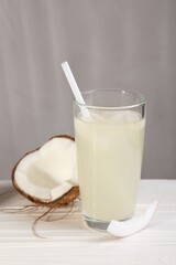Glass of coconut water and nut on white wooden table