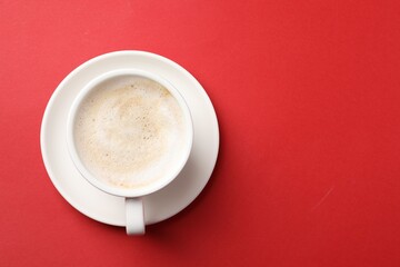 Cup of aromatic coffee on red background, top view. Space for text