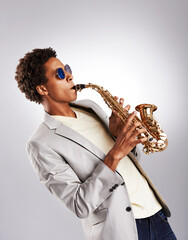 Saxophone, man and performance with jazz artist, creative and music on a grey studio background....
