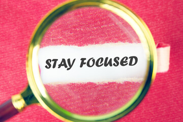 Motivation concept. STAY FOCUSED through a magnifying glass under a torn piece of paper