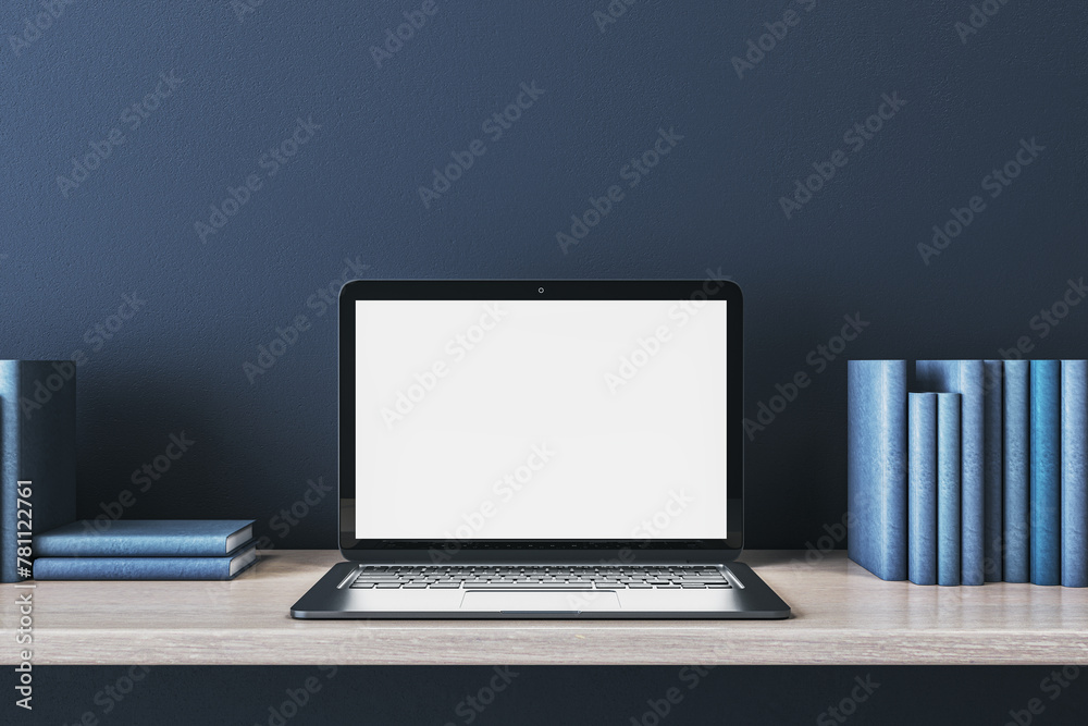 Poster close up of creative wooden designer desk with books and empty white mock up laptop screen on blue c