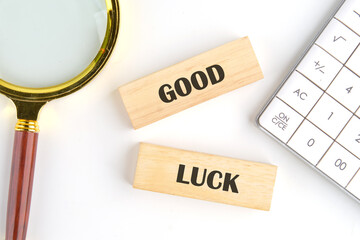 GOOD LUCK symbol on wooden blocks on a white background next to a calculator and a magnifying glass