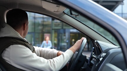 Male sitting in car waiting for daughter looking in window. Rear of male sit in vehicle waits for...