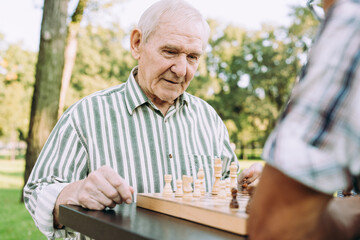 Group of senior friends playing chess at the park