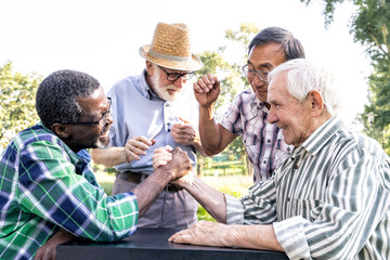 Group of senior friends playing arm wrestling at the park