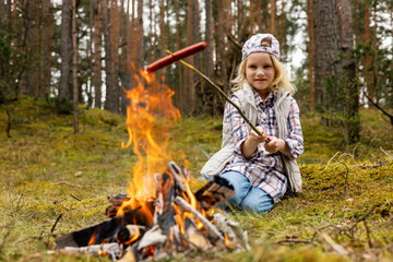 little girl frying sausage over bonfire in forest. outdoor adventures - 781129396