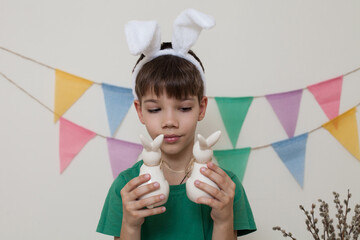 A boy in bunny ears with Easter bunnies in his hands.