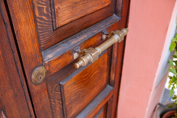 Antique wooden door with gilded handle close-up photo.