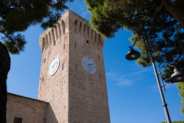 An ancient stone clock tower against a blue sky.