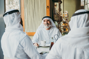 Three business men having a tea in Dubai wearing traditional emirati clothes
