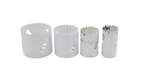 a set of 4 used round hole metal saw blades standing upright used with a drill for cutting opening in wood isolated on white background