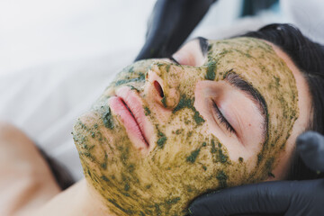 A beautician makes a mask on a woman's face. Mask-peeling for the face, spa procedures, skin care. A woman receives facial care from a beautician