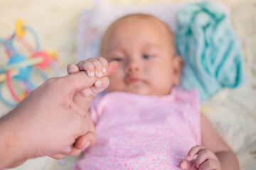 Infant Baby Girl is holding on to her father’s finger. 