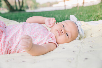Infant Baby Girl is laying on her back in a pink bodysuit.