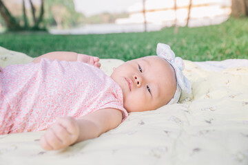 Infant Baby Girl is laying on her back in a pink bodysuit.