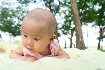 Infant Baby Girl is laying on her belly in a pink bodysuit, holding her head up.