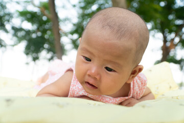 Infant Baby Girl is laying on her belly in a pink bodysuit, holding her head up.