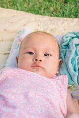 Infant Baby Girl is laying on her back in a pink bodysuit.