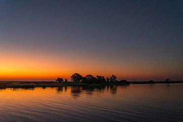 Sonnenuntergangs und Silhouette von Bäumen spiegeln sich im Chobe Fluss, Botswana