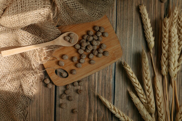 Breakfast cereal, bran with wooden spoon and ears of corn on wooden background