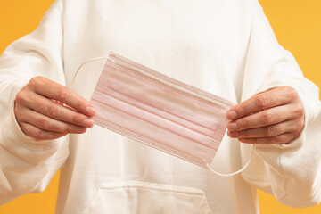 Person holding a pink surgical mask unfolded