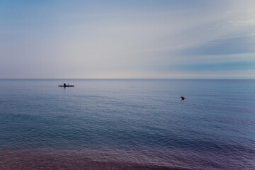Sea, calm, a lonely fisherman's boat near the shore and a red buoy