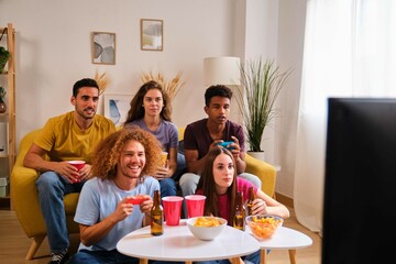 Group of friends play video games together at shared flat, having fun.