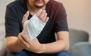Man with a gauze bandage wrapped around his hand. First aid, accident and injury treatment concept.