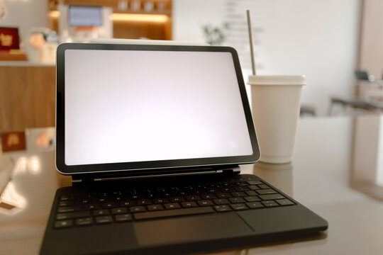 Photo of notebook showing white blank screen while someone working online at cafe, white coffee drink putting next to laptop.
