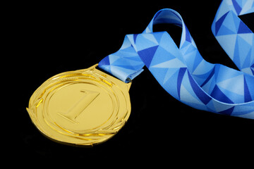 Gold medal with blue ribbon isolated on black background.	