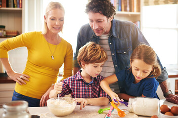 Mother, father and children in kitchen baking cookies for learning, development and bonding as...