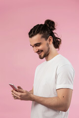 A man on a pink background looks into a smartphone
